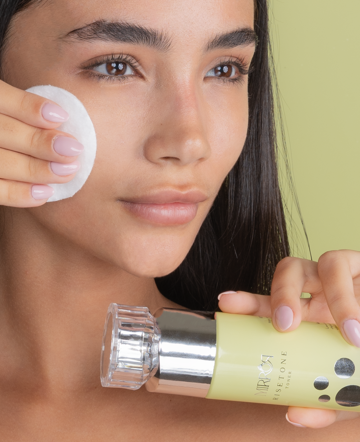 Model applying Mirror Skin Risetone Toner with a cotton pad on her cheek.