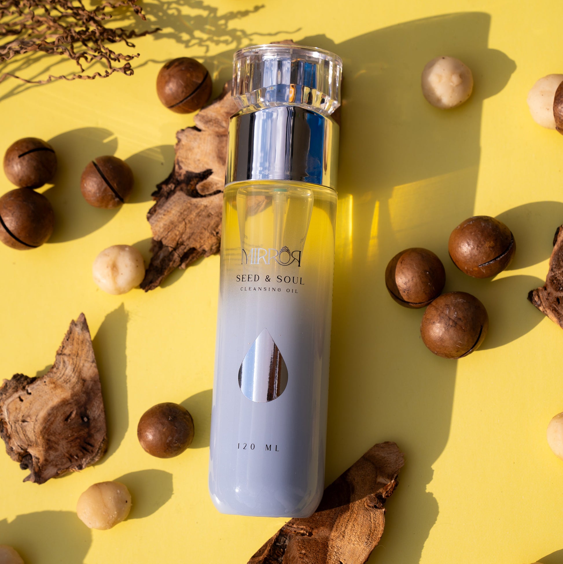 Mirror Skin Seed & Soul Nourishing Cleansing Oil bottle displayed with macadamia nuts and natural oils, highlighting clean vegan skincare ingredients.