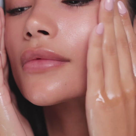 Model gently massaging Mirror Skin Seed & Soul Cleansing Oil on her face
