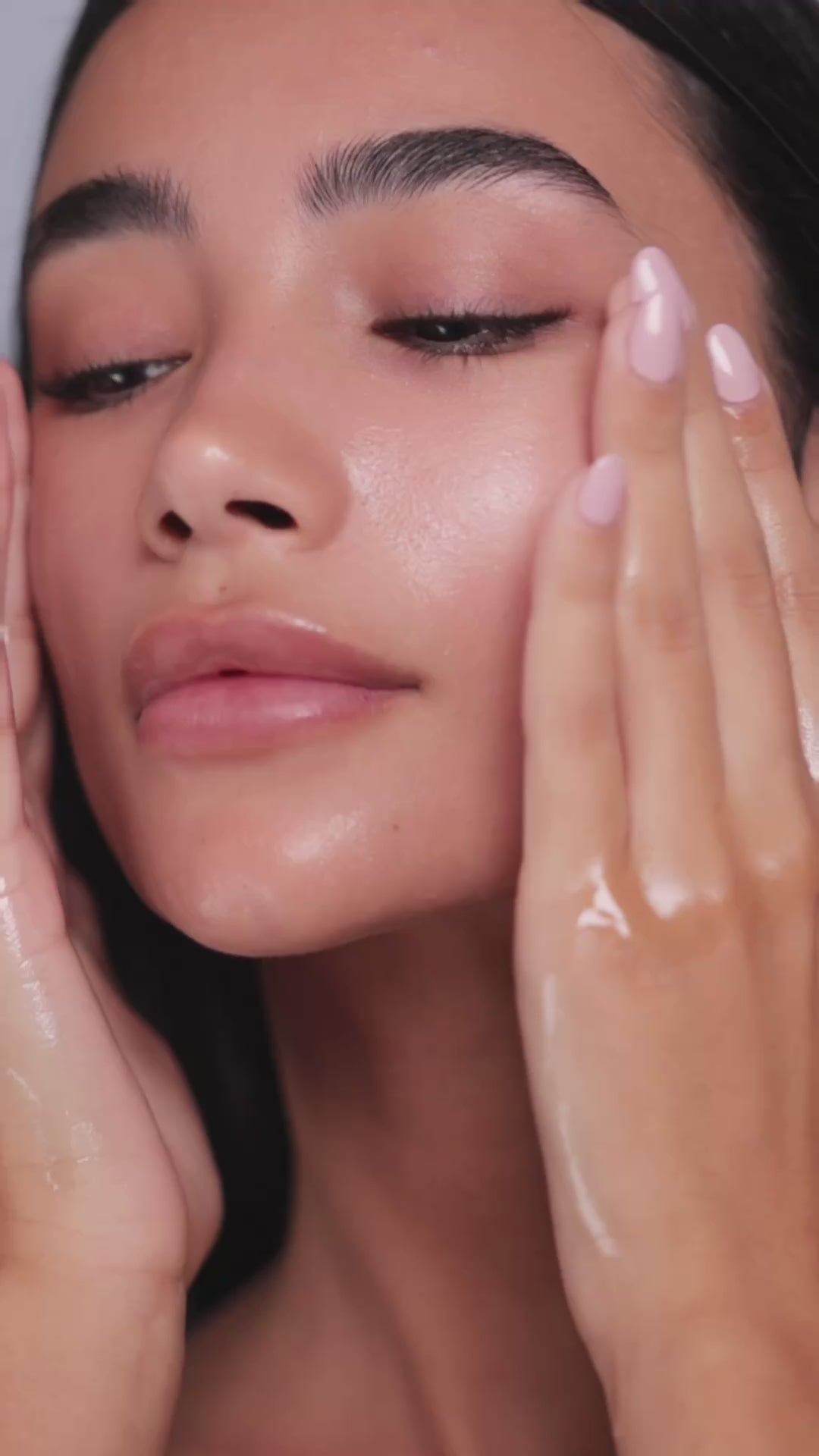 Model gently massaging Mirror Skin Seed & Soul Cleansing Oil on her face